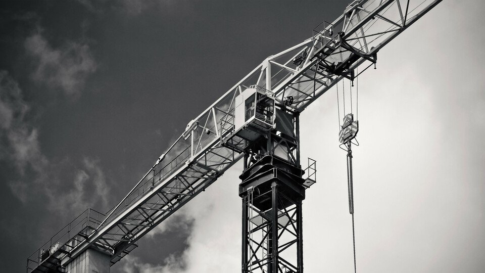 Solider Kran auf Baustelle unter dunklen Wolken.