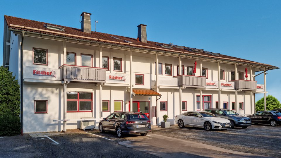 Mehrstöckiges Fischer-Firmengebäude mit Parkplatz.