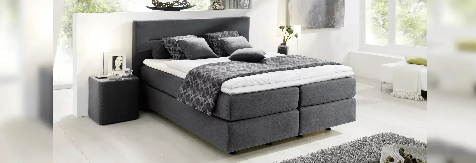 Moderne graue Schlafzimmereinrichtung mit Boxspringbett.