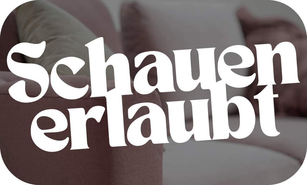 Werbebanner mit der Aufschrift ‚Schauen erlaubt‘ vor unscharfem Hintergrund einer gepolsterten Sitzlandschaft in warmen Farbtönen.