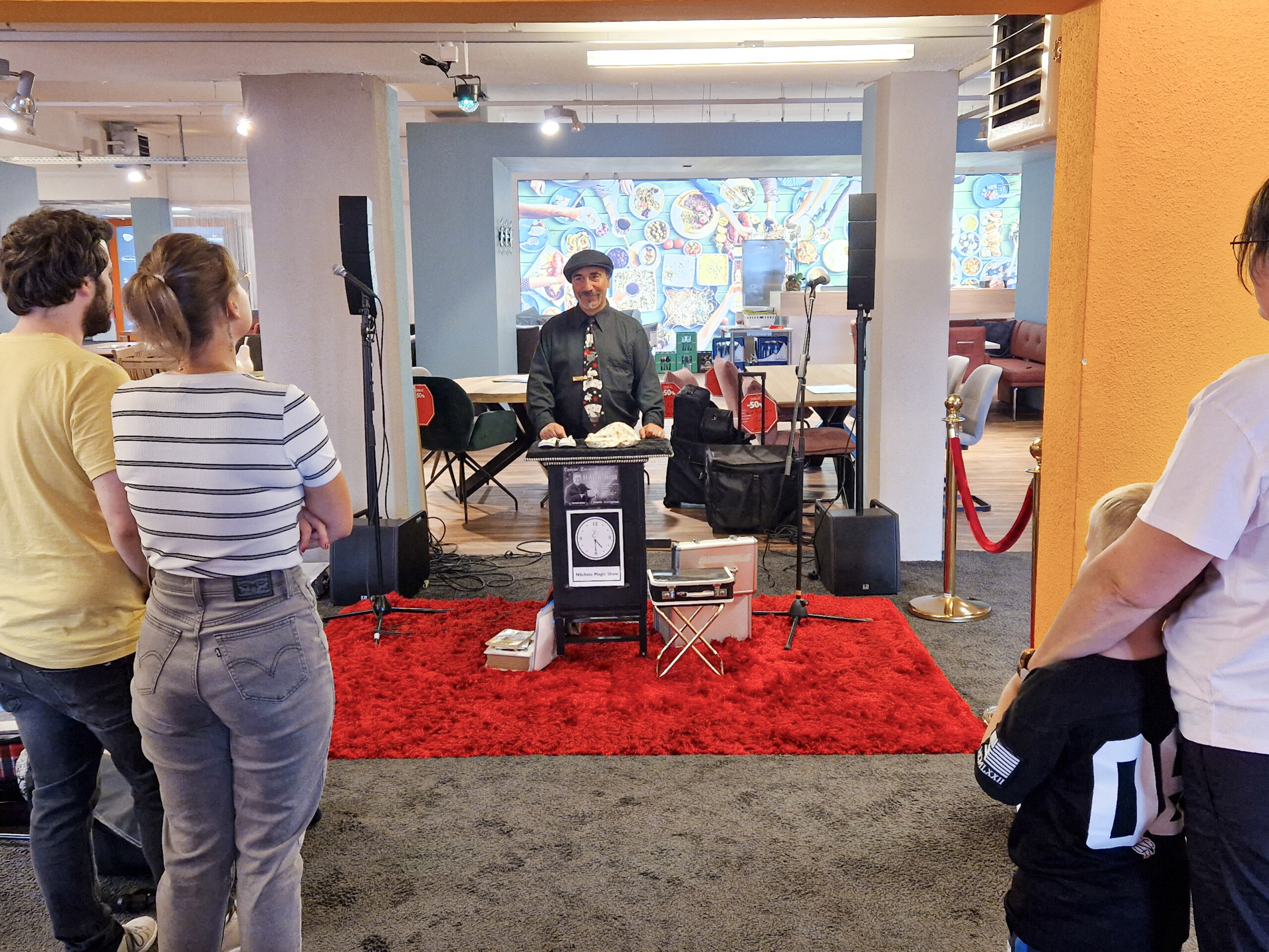Bühne mit Performer und Publikum in kreativem Raum.