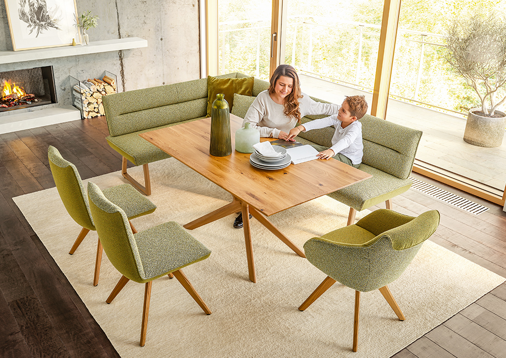 Familienfreundliche Essgruppe mit grün gepolsterten Stühlen und Eckbank sowie Massivholztisch – gemütliches Esszimmer im skandinavischen Stil mit Kamin. 3. Polstermöbel Fischer – Detailaufnahme der gepolsterten Essbank mit Holzg