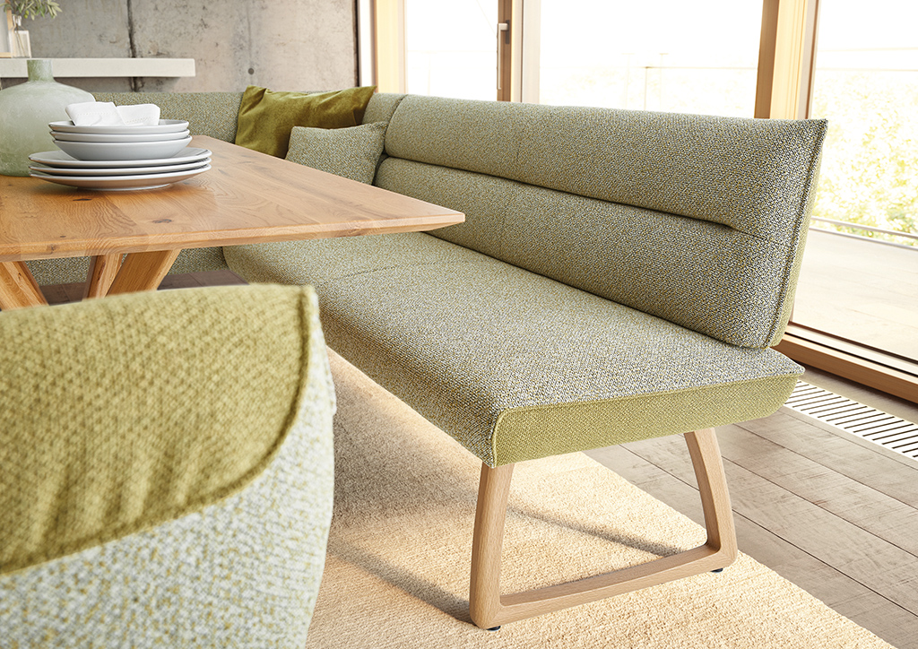 Bequeme Essbank mit grüner Polsterung und geschwungenem Holzgestell – hochwertiges Sitzmöbel für moderne Essbereiche mit natürlichem Flair.