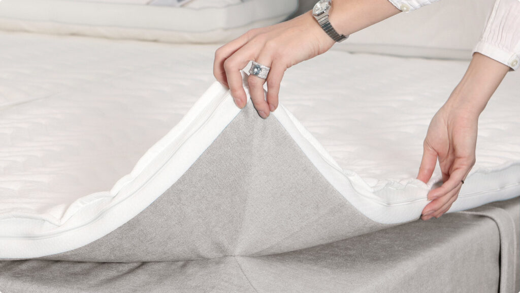 Hand hebt Topper eines Boxspringbetts an