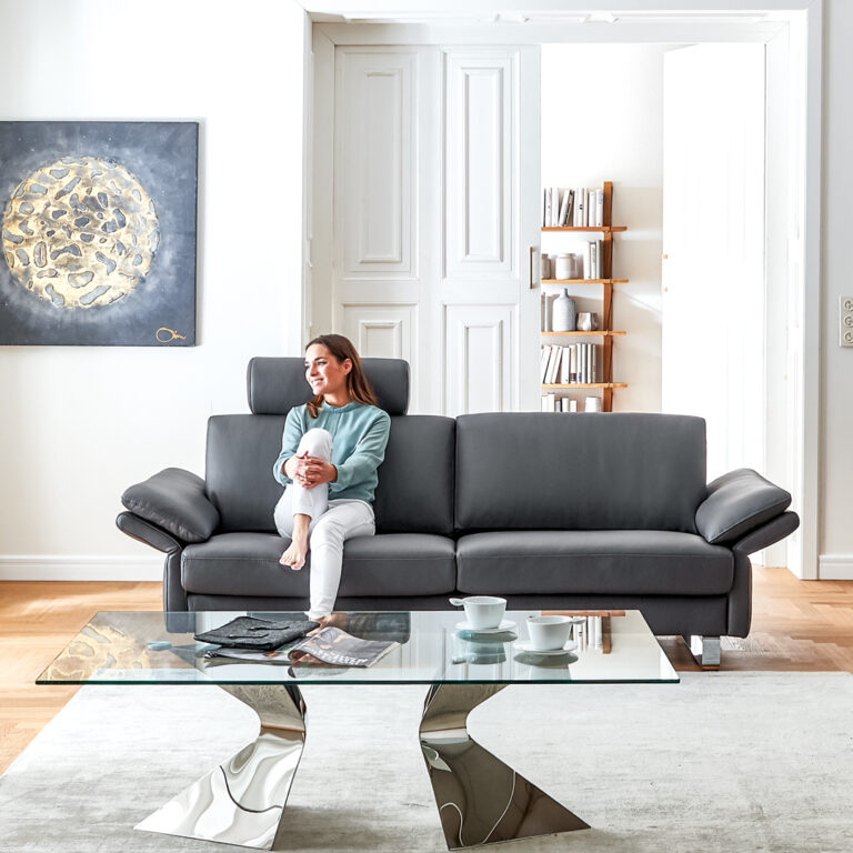 Frau sitzt auf der Couch in modernem Wohnzimmer.