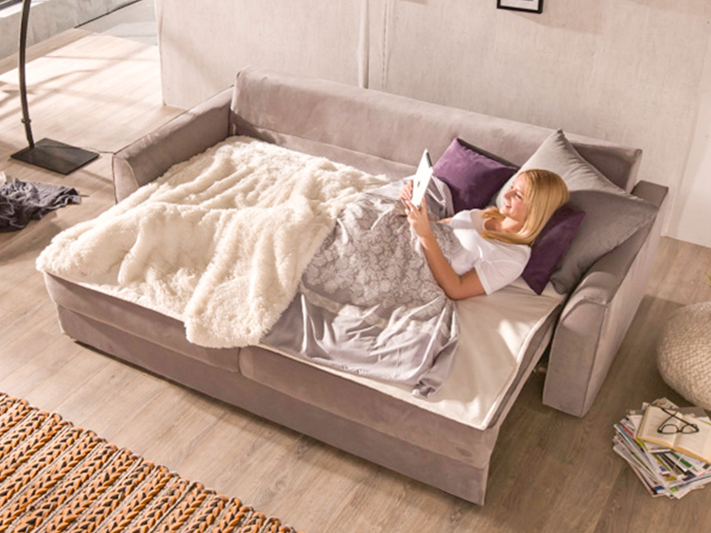 Blonde Frau liest Buch auf Sofa in Wohnzimmer.