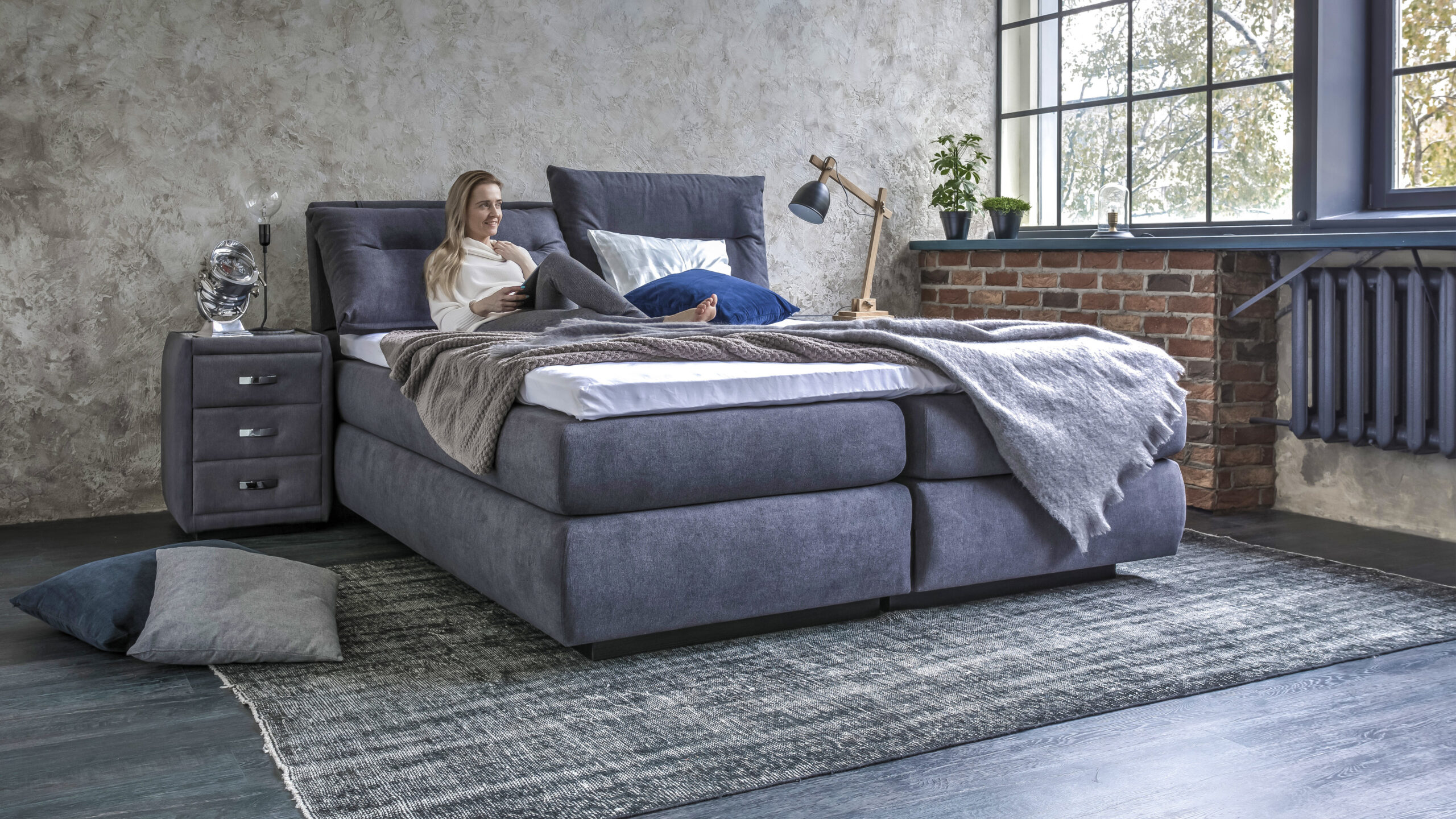 Ein gemütliches Schlafzimmer mit grauem Boxspringbett.