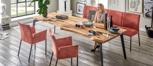 Gemütliches Loft-Interieur mit Holztisch und roten Stühlen.