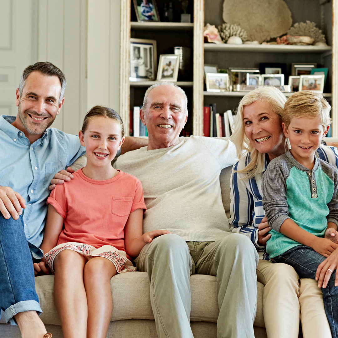 Eine fröhliche Familie sitzt zusammen auf einer Couch.