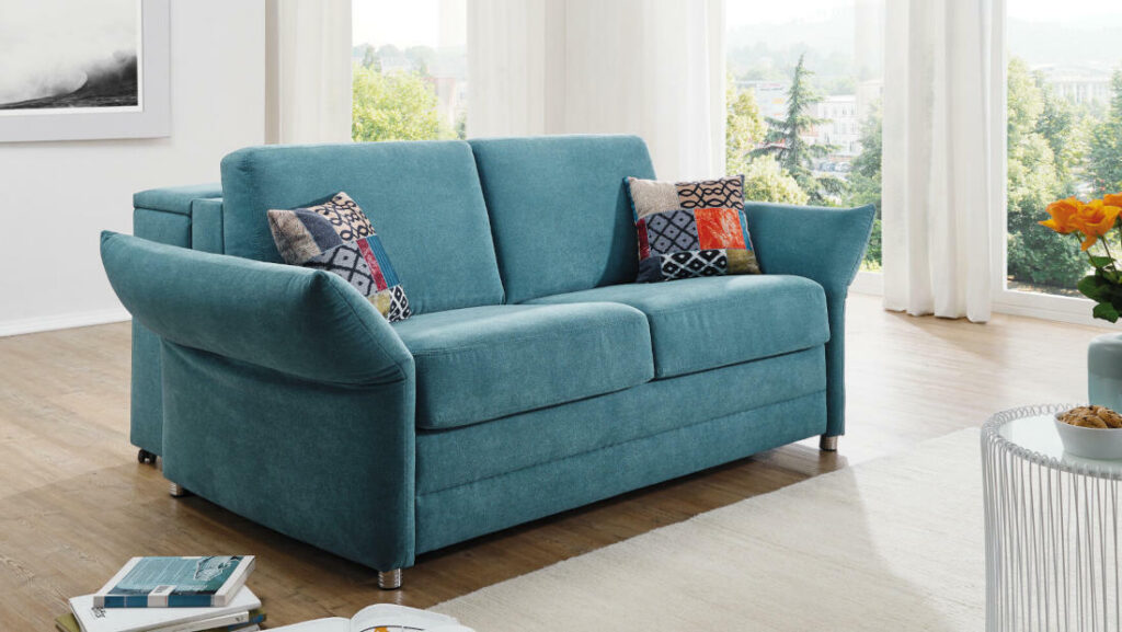 Komfortables teal-farbenes Sofa mit gemusterten Kissen.