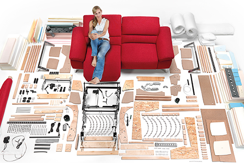 Woman relaxing on red couch among construction supplies.