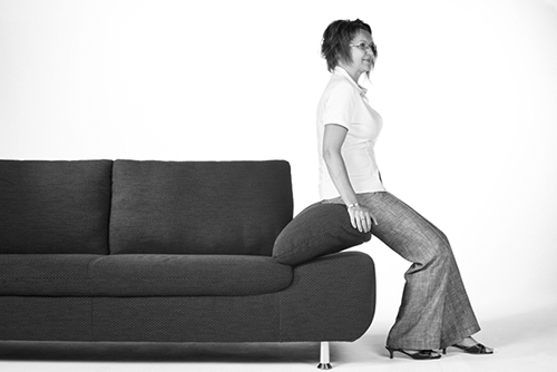Frau posiert sitzend auf Sofa in schwarzweiß.