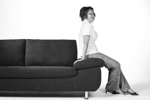 Person sitzt auf schwarzem Sofa.