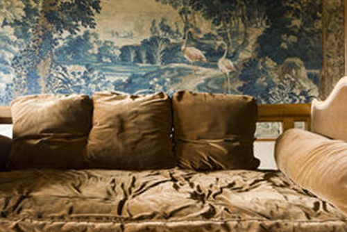 Gemälde mit Landschaft hinter Sofa mit Kissen.