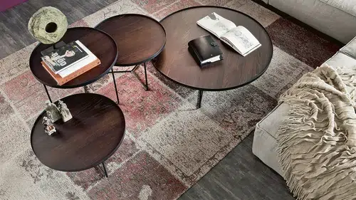 Gemütliches Wohnzimmer mit Holztischen und Teppich.