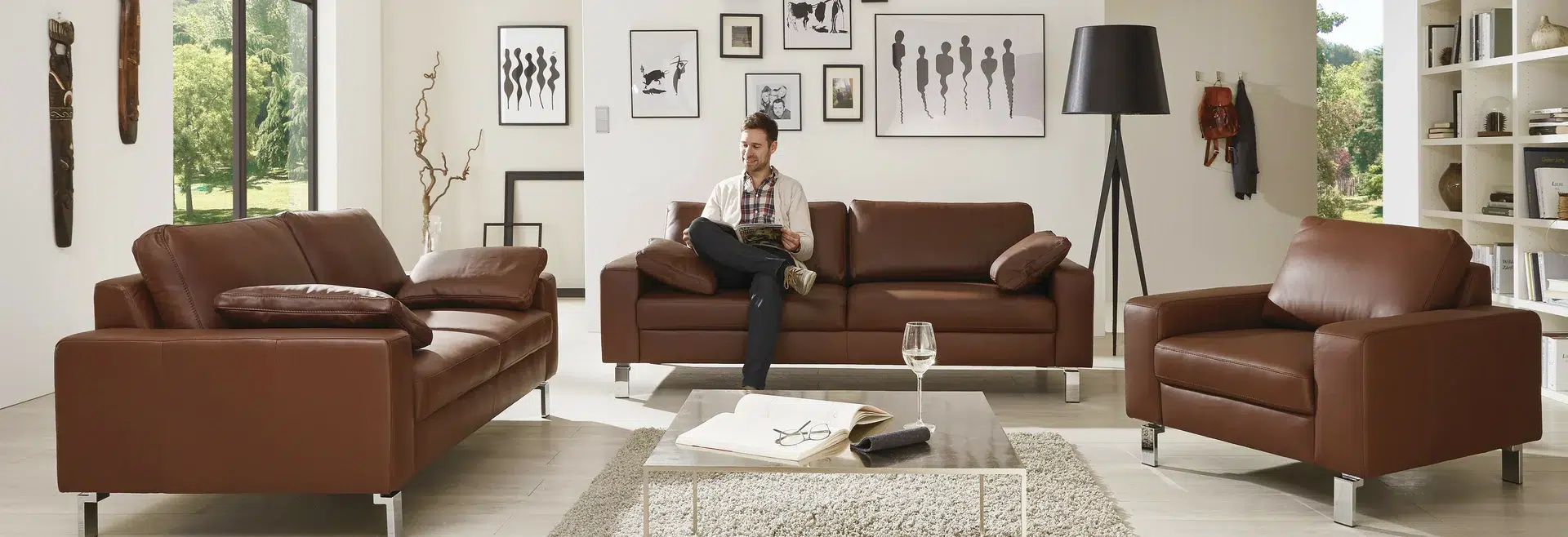 Mann sitzt auf Ledercouch und liest.