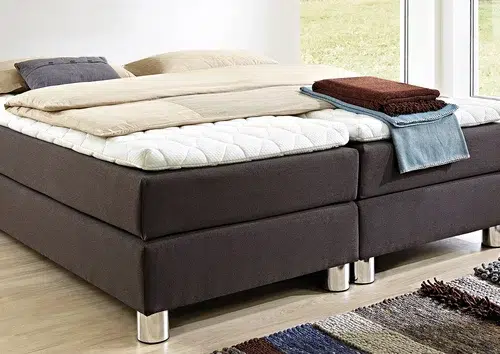 Bett mit weißer Bettwäsche und braunen Textilien.