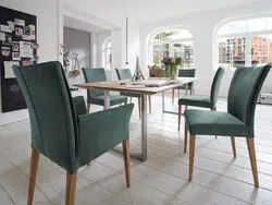 Geräumiges Wohnzimmer mit modernem Holztisch und grünen Stühlen