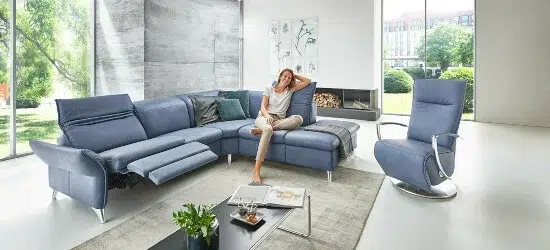 Frau entspannt auf grauem Sofa in moderner Wohnzimmerumgebung.