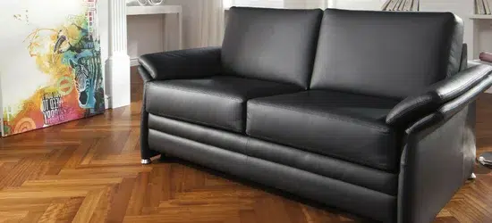 Schwarze, moderne Ledercouch in geräumigem Wohnzimmer.
