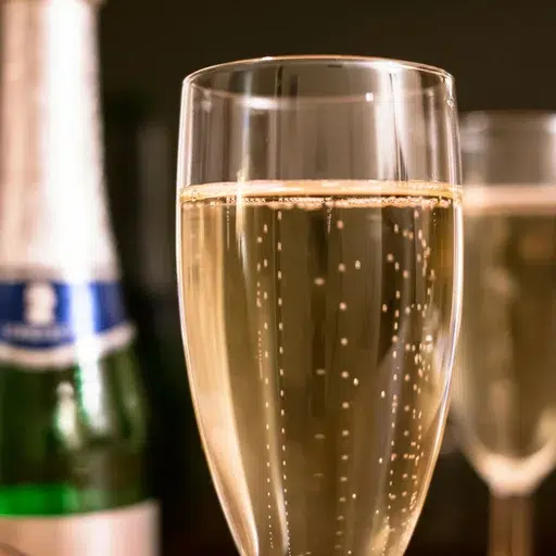 Glas mit schäumendem Champagner auf schwarzem Hintergrund.