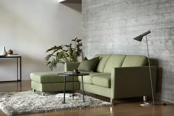 Modernes, grünes Wohnzimmer mit Sofa und Tisch.