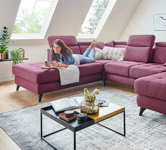 Frau entspannt auf violetter Couch in Wohnzimmer.
