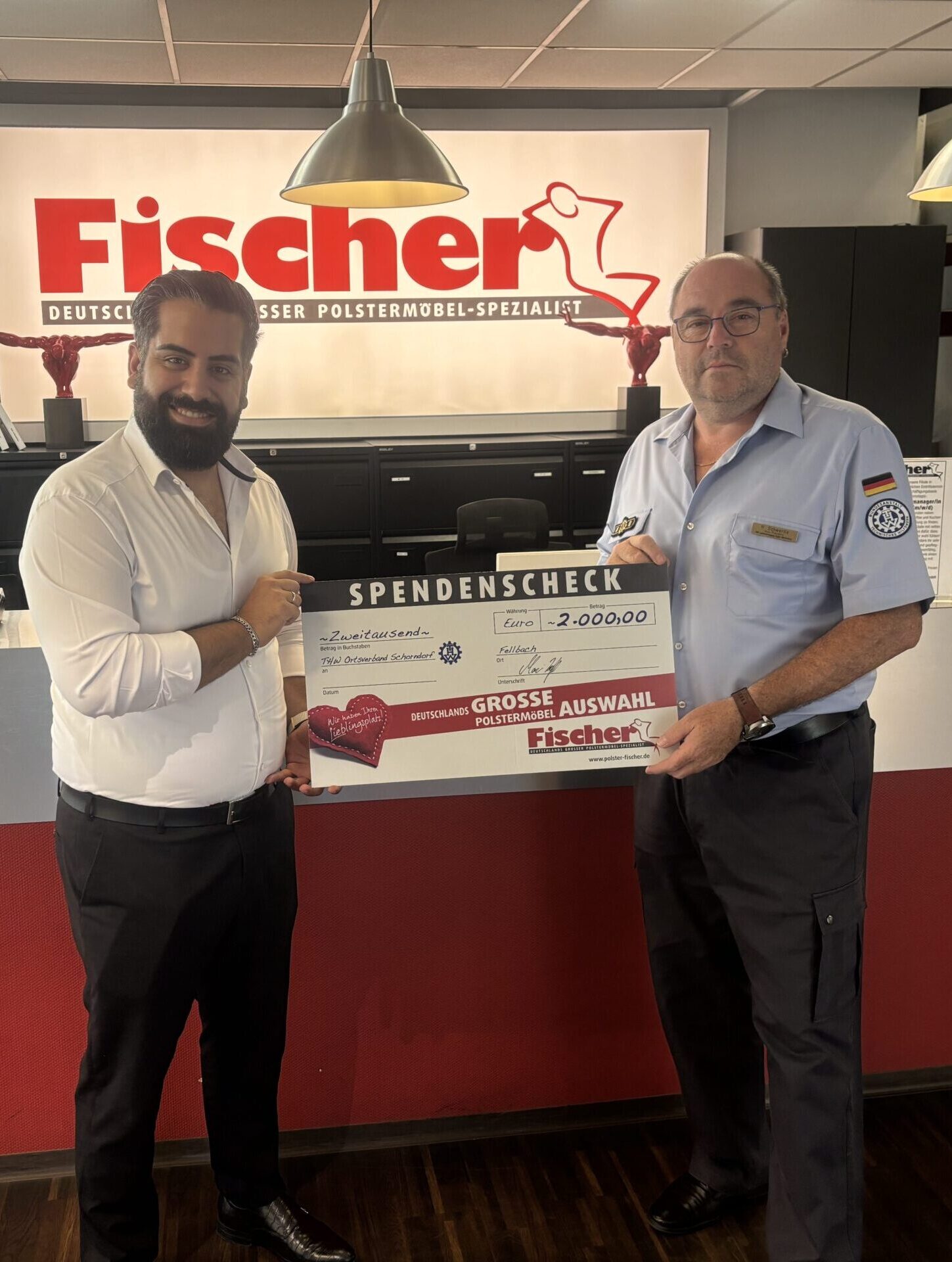 Zwei Männer übergeben Fischer großen Spendenscheck.