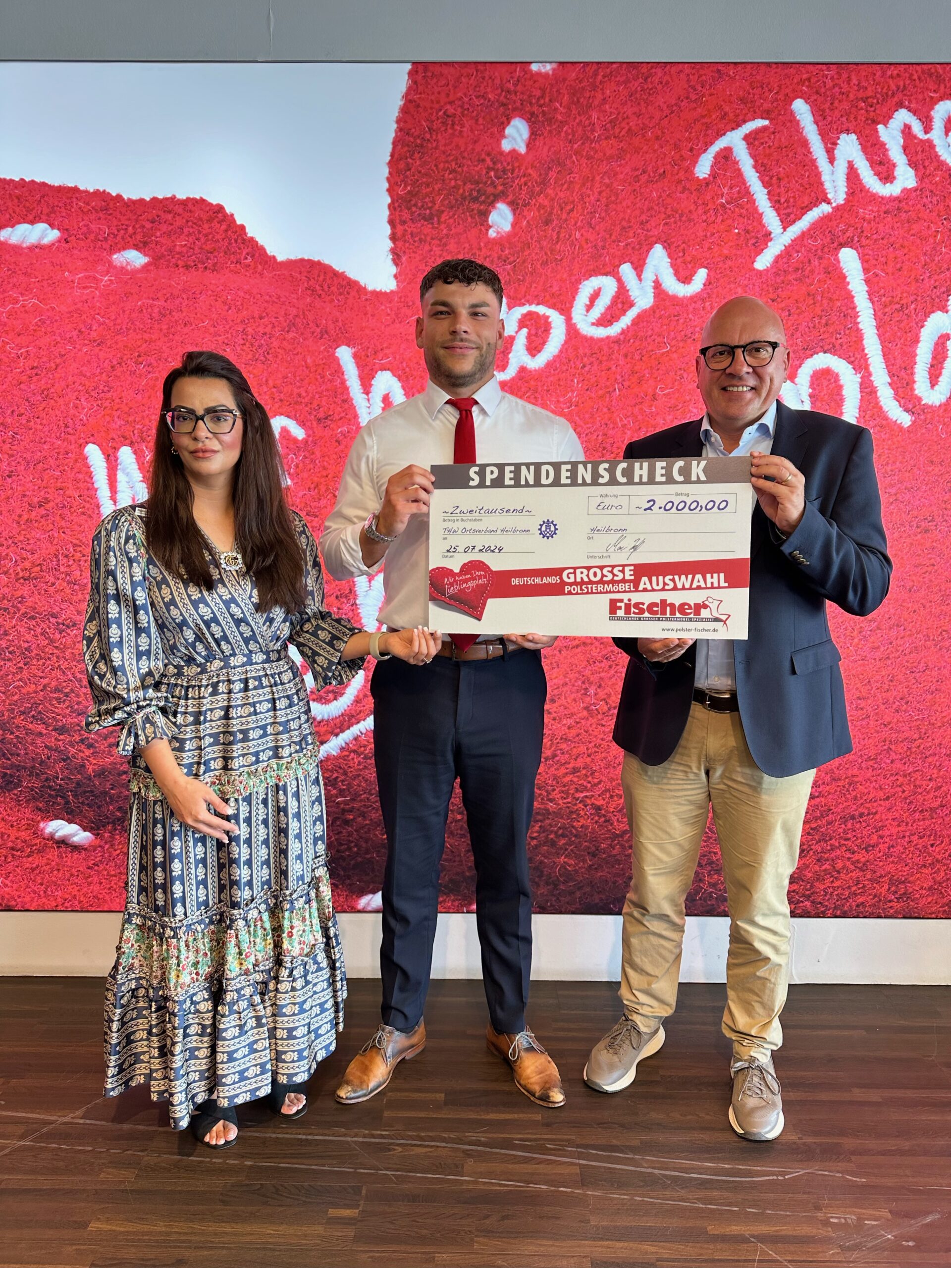 Menschen übergeben Spendenschein für 2.000 Euro.