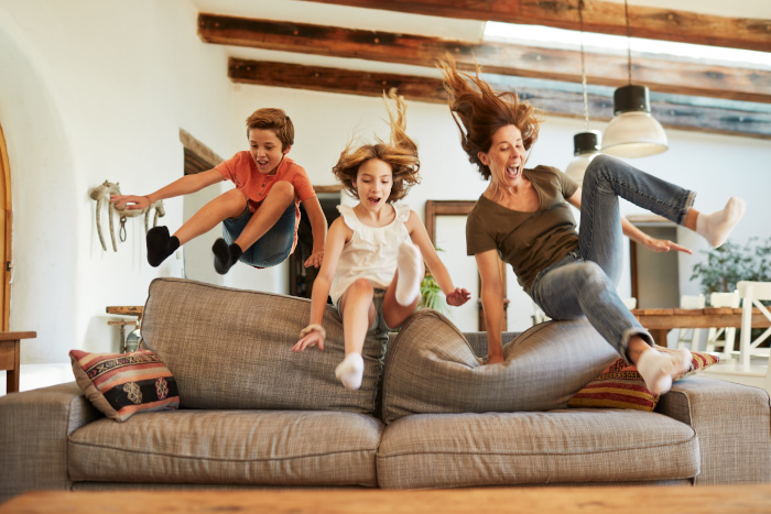 Familie springt schwungvoll auf das Sofa