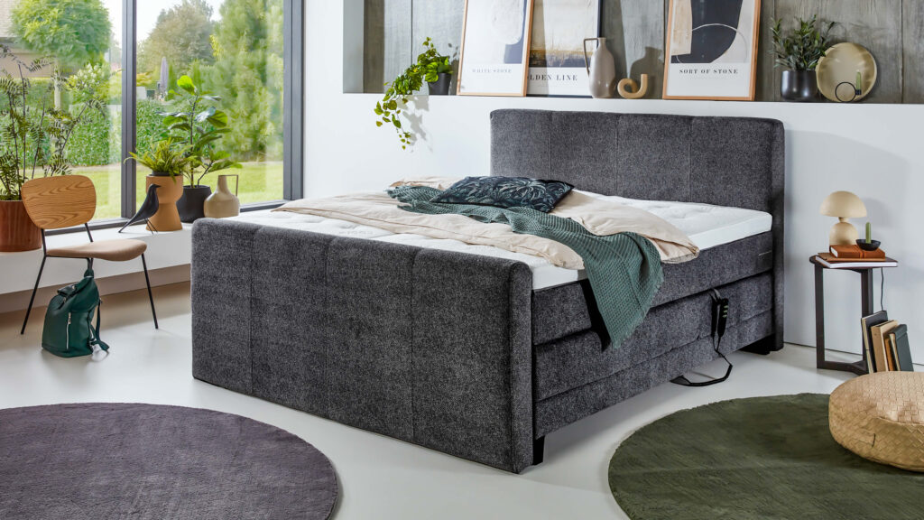 Elektrisch verstellbares Boxspringbett mit aufgerichtetem Kopfteil in modernem Schlafzimmer