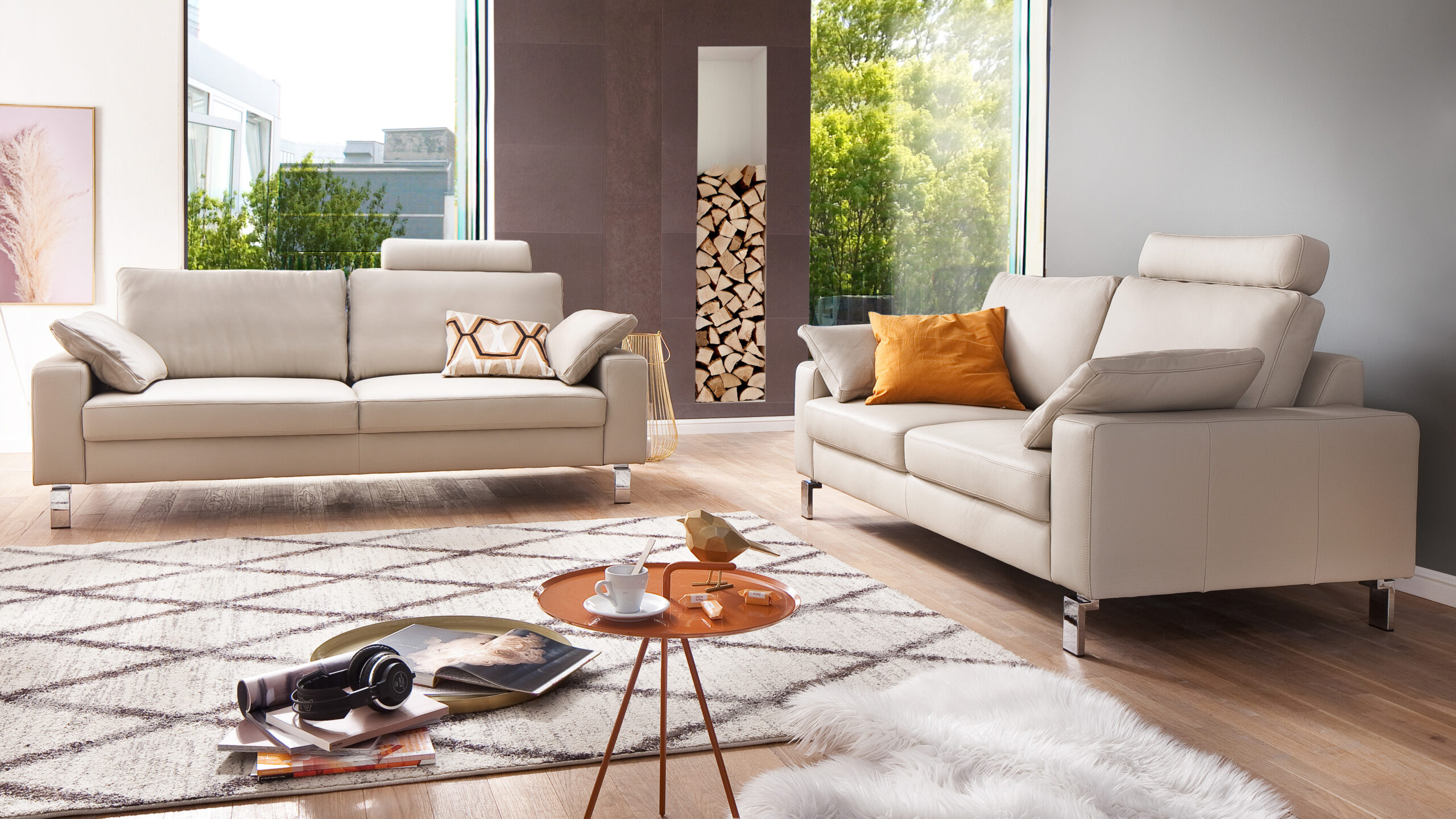 Zwei elegante Einzelsofas in cremefarbenem Leder in einem hellen Wohnzimmer mit großen Fenstern, gemütlicher Teppich- und Dekotischgestaltung