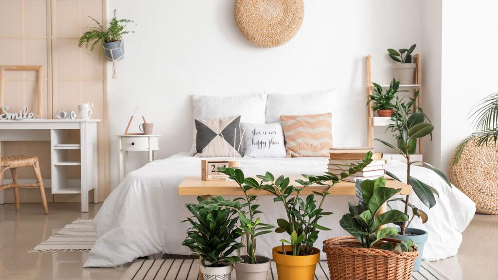 Helles Schlafzimmer im Boho-Stil mit weißen Textilien, Naturholzmöbeln und vielen Zimmerpflanzen – gemütliche Wohnidee von Polstermöbel Fischer.