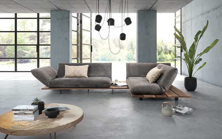 Graues Daybed-Sofa mit Holzplattform in modernem Loft mit großen Fenstern und minimalistischer Einrichtung