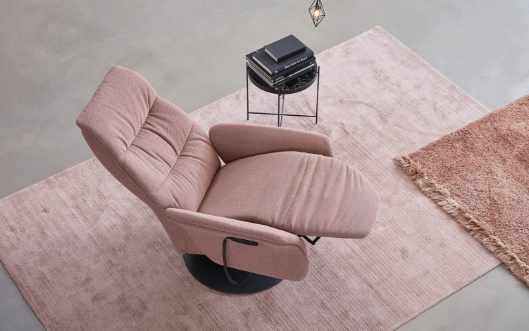 Rosa Relaxsessel in Draufsicht auf hellem Teppich mit kleinem Beistelltisch im minimalistischen Wohnstil