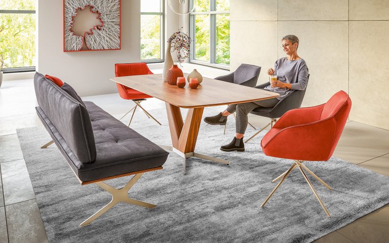 Esszimmer mit Holztable, Polsterbank und roten sowie grauen Drehstühlen in modernem Interior