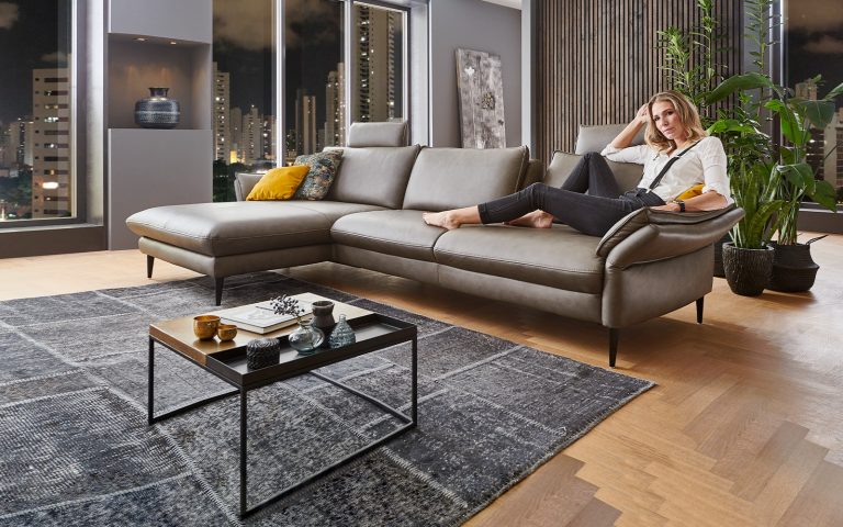 Graues Lederecksofa in modernem Wohnraum mit Stadtblick, Teppich und stilvoller Einrichtung bei Nacht