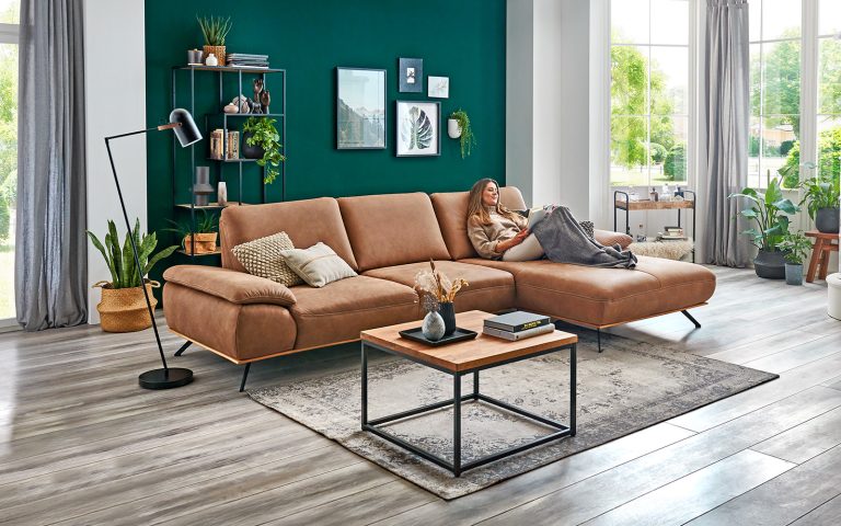 Braunes Ecksofa in modernem Wohnzimmer mit grüner Wand, Couchtisch und dekorativen Pflanzen